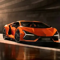 Pomarańczowy Lamborghini Revuelto błyszczy w świetle, gotowy do jazdy.
