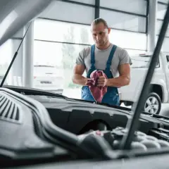 Mechanik z ręcznikiem przy silniku. Rozważasz naprawa samochodu w leasingu a koszty? Sprawdź, co obejmuje umowa.