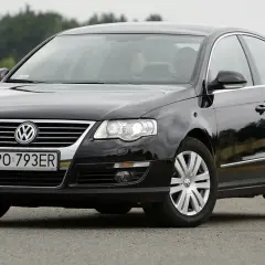 Czarny Passat B6 z polskimi tablicami PO 793ER na tle zieleni.