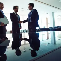Biznesmeni uścisnęli sobie dłonie, finalizując umowę leasing na spółkę zoo. W tle widać salę konferencyjną.
