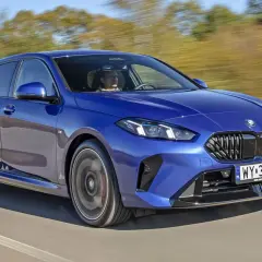 Niebieskie BMW Seria 1 pędzi po drodze, kierowca skupiony na trasie.
