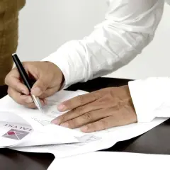 Mężczyzna w białej koszuli podpisuje dokumenty. Ubezpieczający i ubezpieczony finalizują umowę.