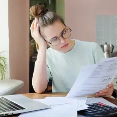 Zmartwiona kobieta analizuje dokumenty, szukając informacji o zwrot składki za niewykorzystany okres ubezpieczenia OC.