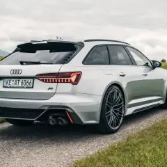 Białe Audi RS6 C8 z pakietem ABT na tle zielonych wzgórz. Widok z tyłu na sportowe detale i felgi.