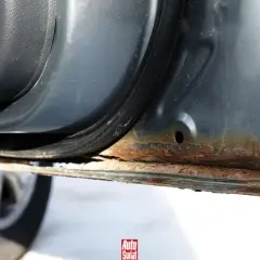 Widoczna rdza na samochodzie, szczególnie na progu drzwi, świadczy o postępującej korozji.