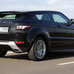 Czarny Land Rover Evoque jedzie po drodze, widać jego tylną część i obręcz koła w ruchu.