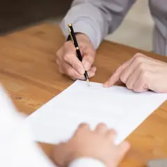 Dłoń podpisuje dokument, wskazując na kluczowe punkty umowy. To dowód na leasing uproszczony, który ułatwia szybkie transakcje.