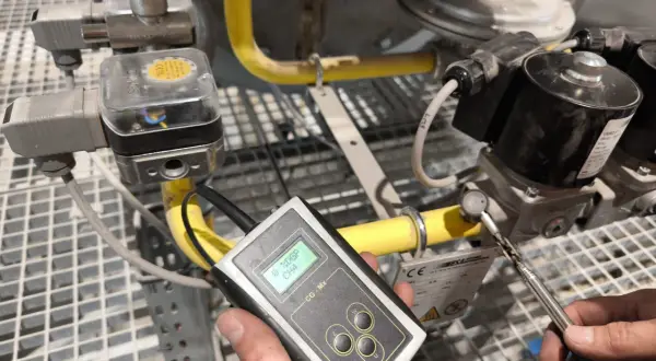 Technik przeprowadza sprawdzenie szczelności instalacji gazowej za pomocą detektora.