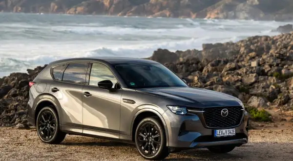 Szary SUV Mazda CX-60 na tle skalistego wybrzeża. To jeden z rodzajów hybryd, który łączy moc z ekologią.