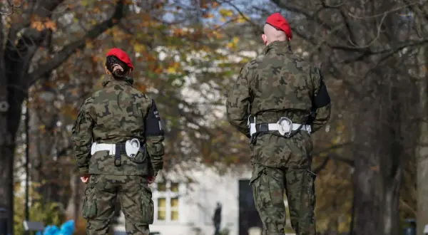 Dwóch żołnierzy w mundurach moro i czerwonych beretach stoi na tle drzew. Czy wojsko może zabrać samochód? To pytanie pozostaje bez odpowiedzi.