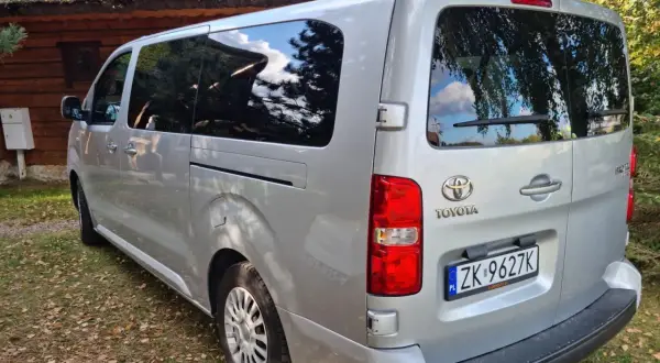 Srebrna Toyota z tablicą ZK 9627K, idealna na cesja leasingu. Zaparkowana przy drewnianym domu z krytym strzechą dachem.