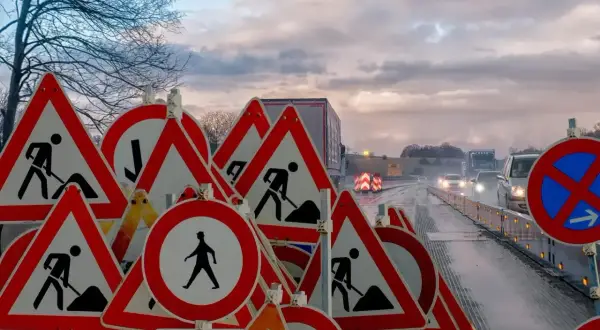 Mnóstwo znaków drogowych "roboty drogowe" i "piesi" wzywa do szczególna ostrożność na mokrej drodze.