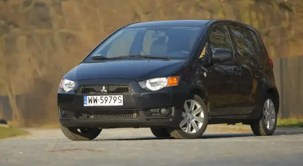 Czarny Mitsubishi Colt na drodze, gotowy do podróży.