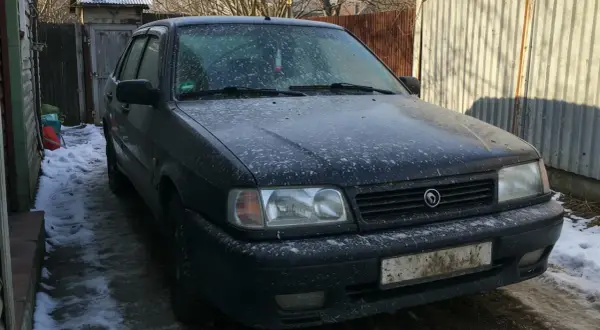 Ciemny samochód pokryty śniegiem i błotem, wyglądający jakby groził mu mandat za brudne auto.