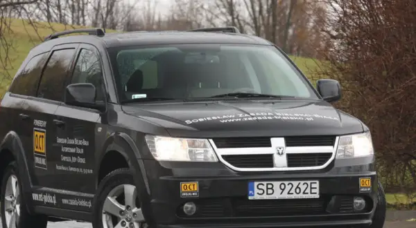 Czarny Dodge Journey z naklejkami "OCT UWOLNIJ MOC" i "Sobiesław Zasada Bielsko-Biała".
