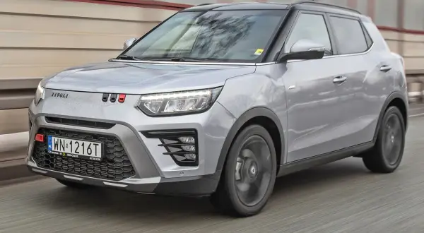 Srebrny SsangYong Tivoli z czarnym dachem pędzi po drodze.