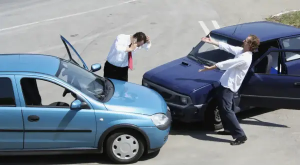 Pożyczenie samochodu koledze skończyło się stłuczką. Jeden z mężczyzn nerwowo rozmawia przez telefon, drugi rozkłada ręce w geście bezradności.