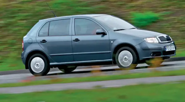 Szara Skoda Fabia 1 w ruchu, z rozmytym tłem zieleni i drogi.