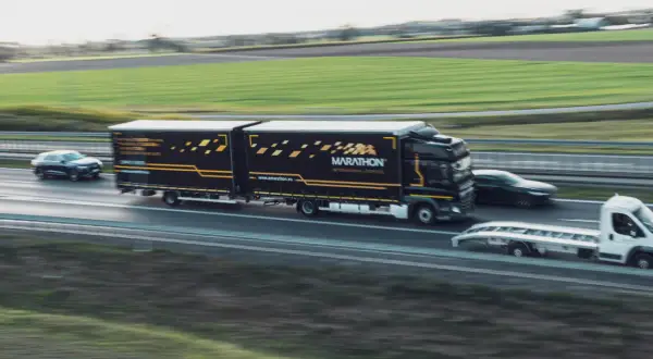 Ciężarówka Marathon International Logistics z naczepą jedzie autostradą. To część pakietu mobilności, który zapewnia sprawny transport.