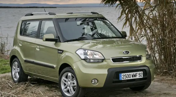 Zielony Kia Soul zaparkowany nad jeziorem, otoczony trzcinami.
