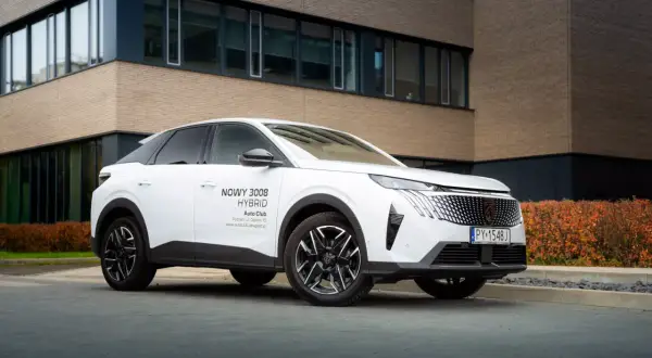 Biały Peugeot 3008 hybryda plug-in zaparkowany przed nowoczesnym budynkiem.