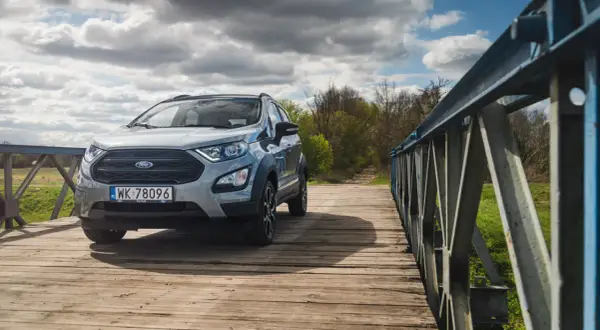 Srebrny Ford Ecosport na drewnianym moście, gotowy na przygodę.