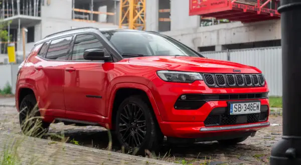 Czerwony Jeep Compass na tle budowy. Elegancki SUV gotowy na miejskie wyzwania.