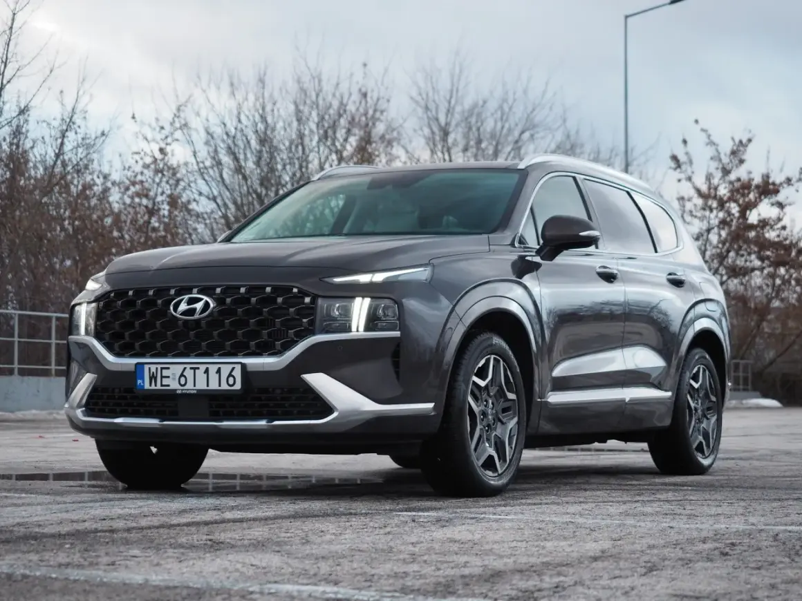 Ciemnoszary Hyundai Santa Fe z polskimi tablicami WE 6T116 stoi na parkingu.