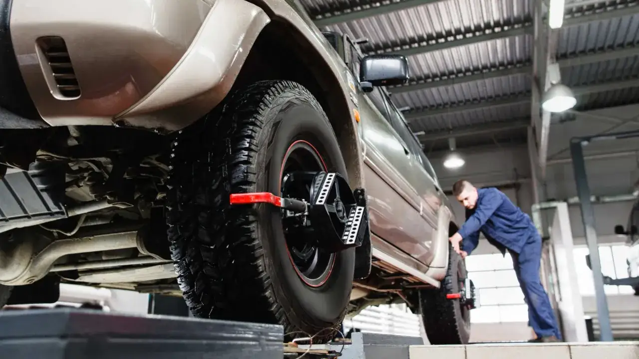 Mechanik sprawdza geometrię kół SUV-a na podnośniku.