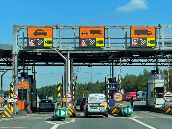 Bramki A4 z wyświetlaczami informującymi o typie pojazdu i opłatach. Samochody i ciężarówki zbliżają się do punktów poboru opłat.